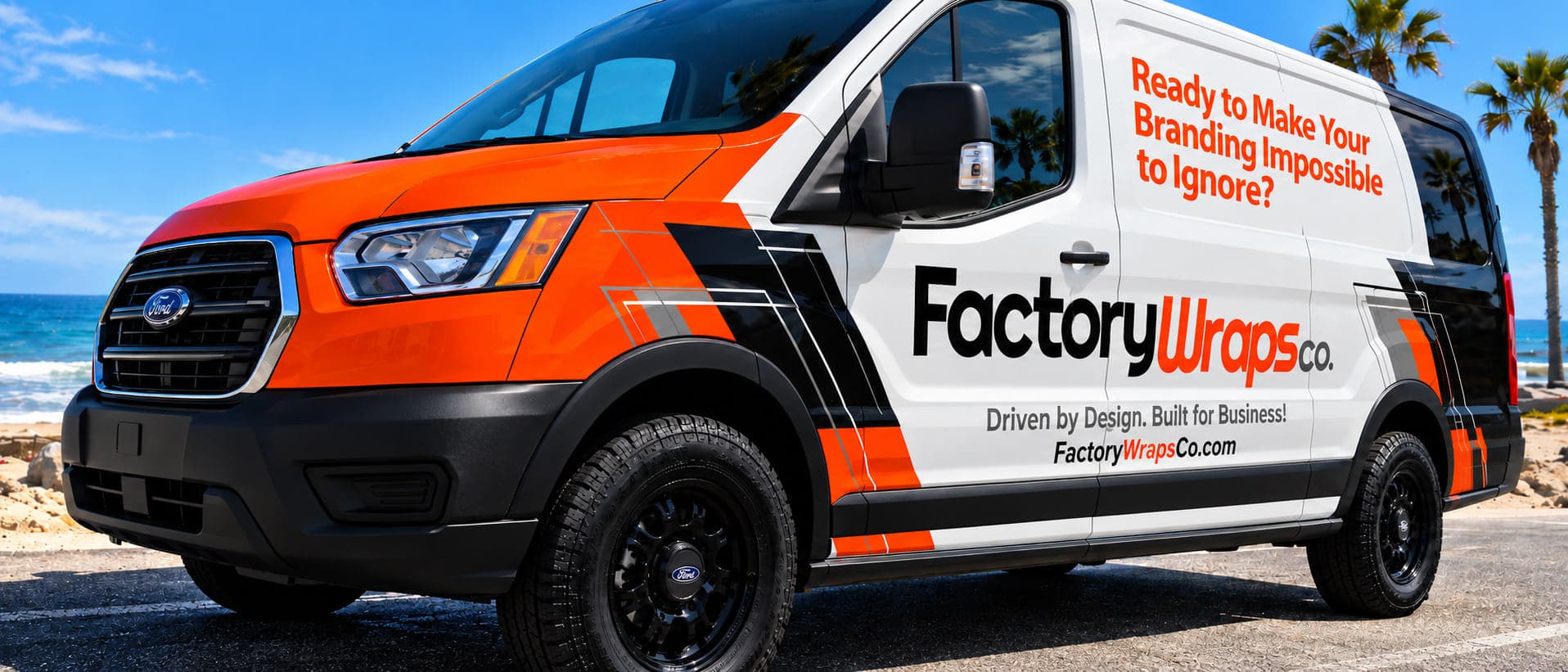 Factory Wraps Co. cargo van wrapped in orange, white, and black graphics, parked on the Southern California coast